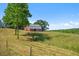 Quaint red barn surrounded by green trees and a grassy field under a clear, blue sky at 220 Mountain Creek Rd, Bowdon, GA 30108