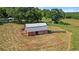 Rustic red barn with a silver roof in a grassy field with an adjacent wooded area at 220 Mountain Creek Rd, Bowdon, GA 30108