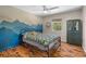 Cozy bedroom with hardwood floors and a vibrant wall mural, illuminated by a ceiling fan at 220 Mountain Creek Rd, Bowdon, GA 30108