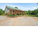 Inviting home featuring a green roof, long porch, landscaped yard, and spacious gravel driveway at 220 Mountain Creek Rd, Bowdon, GA 30108