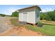 Exterior view of a storage shed with a metal roll-up door and small window, surrounded by a landscape of grass and trees at 220 Mountain Creek Rd, Bowdon, GA 30108