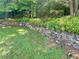 Landscaped backyard featuring a stone retaining wall and lush greenery, adding natural beauty to the property at 1028 Gate Post Ln, Lawrenceville, GA 30044