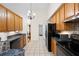 Kitchen with wood cabinets, tile floors, and modern appliances, illuminated by a chandelier at 390 Rock Springs Pass, Dallas, GA 30157