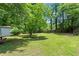 Large, grassy backyard with mature trees and a storage shed, great for outdoor activities at 143 Frances Dr, Dallas, GA 30157