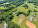An aerial view of a property with a long driveway, mature trees, open fields, and various outbuildings at 226 Euharlee Five Forks Rd, Kingston, GA 30145