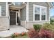 Inviting home entrance featuring stone accents and a dark-stained front door surrounded by colorful landscaping at 242 Aspen Way, Dallas, GA 30157