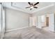 Main bedroom featuring neutral carpet, tray ceiling, two windows, and an adjoining bathroom and closet at 242 Aspen Way, Dallas, GA 30157
