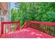 A vibrant red wooden deck with green foliage backdrop, perfect for outdoor relaxation and entertaining at 4348 Tillage Path, Douglasville, GA 30135
