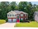 Charming two-story home with a manicured lawn, red stairs, a two-car garage, and a beautifully landscaped yard at 4348 Tillage Path, Douglasville, GA 30135