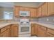 Galley kitchen with wooden cabinetry and white appliances including a range and microwave at 580 Camry Cir, Dallas, GA 30157