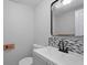 Modern powder room featuring stylish sink, mirror, mosaic backsplash, and neutral color scheme at 800 Post Road Cir, Stone Mountain, GA 30088