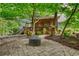 Stone patio with a gas firepit, lush landscaping, and a view of the home's screened porch at 2165 Robin Hood Trl, Cumming, GA 30040