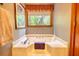 A close-up of a soaking tub with a window overlooking lush greenery, creating a private spa at 2165 Robin Hood Trl, Cumming, GA 30040