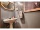 Compact powder room with a pedestal sink, decorative mirror, and soft lighting for guests' convenience at 2165 Robin Hood Trl, Cumming, GA 30040