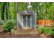 Well-maintained siding shed with double doors and brick-paver path in a wooded backyard at 2165 Robin Hood Trl, Cumming, GA 30040