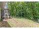 Expansive backyard with lush lawn, tall trees, and stairs leading to screened in porch at 2642 Bridgehampton Sw Rd, Marietta, GA 30064