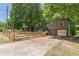 View of the home with a concrete driveway, fenced yard, and mature trees in background at 2642 Bridgehampton Sw Rd, Marietta, GA 30064