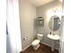 Charming half bathroom with pedestal sink, decorative shelving, and wood flooring at 532 Oakside Pl, Acworth, GA 30102