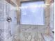 Shower with marble tile surround, shower head, built-in seat, and window at 4085 Fawn Valley Dr, Loganville, GA 30052