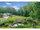 Expansive backyard with a picturesque pond, mature trees, and a charming white house with a three car garage at 590 Arthur Rd, Canton, GA 30115