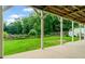 A spacious backyard with a covered patio, green lawn, and view of a wooded area at 590 Arthur Rd, Canton, GA 30115