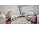Cozy Bedroom features a white crib, comfortable glider chair, and a stylish grey patterned rug over hardwood floors at 1652 Tryon Ne Rd, Atlanta, GA 30319