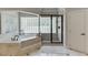 Luxurious bathroom showcasing a soaking tub with glass block window and walk-in shower at 2623 Lindsey Grace Ln, Buford, GA 30519