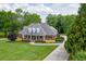 Beautiful brick home with manicured lawn, mature trees, and a welcoming front porch on a sunny day at 2623 Lindsey Grace Ln, Buford, GA 30519