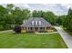Stately brick home with manicured lawn, mature trees, and a welcoming front porch on a sunny day at 2623 Lindsey Grace Ln, Buford, GA 30519