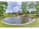 Wide view of the backyard pond with fountain feature, complemented by the exterior home, and lush greenery at 2623 Lindsey Grace Ln, Buford, GA 30519
