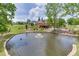 Wide view of the backyard pond with fountain feature, complemented by the exterior home, and lush greenery at 2623 Lindsey Grace Ln, Buford, GA 30519