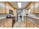 Galley kitchen with stainless steel appliances, light wood cabinets and view to breakfast nook at 638 Oberlochen Way, Douglasville, GA 30134