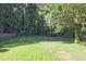 Large, green grass backyard surrounded by mature trees and partial fencing at 1349 Heather Cir, Riverdale, GA 30296