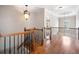 Hallway with hardwood floors, wood and wrought iron banister, and decorative chandelier at 255 Kendemere Pointe, Roswell, GA 30075