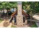 Outdoor kitchen with stone fireplace and manicured landscaping surrounding it at 255 Kendemere Pointe, Roswell, GA 30075