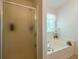 Bright bathroom features a tub under a window next to a glass enclosed shower at 435 Flowering Trl, Grayson, GA 30017