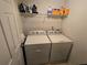 Well-lit laundry room with a modern washer and dryer set with storage shelving at 5578 Swanson Rd, Ellenwood, GA 30294