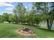 Level lot with a stone fire pit surrounded by mature trees and lush greenery along the lake at 6310 Stillwood Ln, Cumming, GA 30041