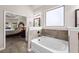 Bright bathroom showing a garden tub with tiled backsplash, neutral paint, and open doorway to the bedroom at 6310 Stillwood Ln, Cumming, GA 30041