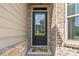 Close up of a front door, showing beige siding, brick facade, and 'Hello' doormat at 6310 Stillwood Ln, Cumming, GA 30041