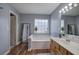 Bright bathroom featuring a soaking tub, vanity with sink, wood-look floors and large mirror at 2908 Cottesford Se Way, Smyrna, GA 30080