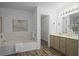 Bright bathroom features a tub, tan cabinets, and wood-look floors leading into the walk-in closet at 402 Roswell Green Ln, Roswell, GA 30075