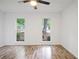 A bedroom with bright light from two windows, light wood floors, and modern ceiling fan at 402 Roswell Green Ln, Roswell, GA 30075