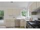 Bright kitchen with stainless steel appliances and view of the landscaped backyard at 402 Roswell Green Ln, Roswell, GA 30075