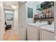 Well-lit laundry room with a washer and dryer unit, plus shelving for storage and access to another room at 1412 Oakridge Cir, Decatur, GA 30033
