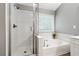 Bright bathroom featuring a glass enclosed shower and separate soaking tub beneath a window at 5060 Winship Ct, Alpharetta, GA 30009