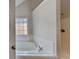 Bright bathroom with a garden tub, white tile surround, and chrome faucet at 514 Jadetree Ln, Atlanta, GA 30349