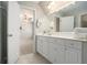 Bright bathroom with white cabinets, tiled floor, large mirror, and connecting doorway to bedroom at 402 Lake Point Trce, Canton, GA 30114