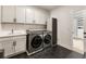 Modern laundry room features sleek washer and dryer, custom cabinets, and stylish black hexagonal tile flooring at 2996 Treeside Ter, Marietta, GA 30066