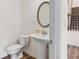 The powder room features a pedestal sink, round mirror, and wood-look floors at 3390 Meadow Grass Drive, Dacula, GA 30019